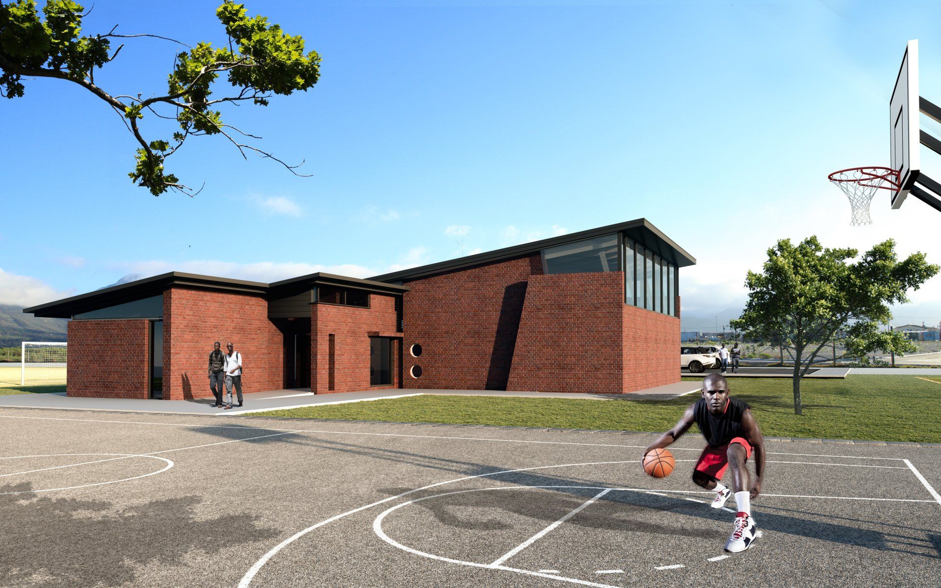 A man is playing basketball on a court in front of a brick building.
