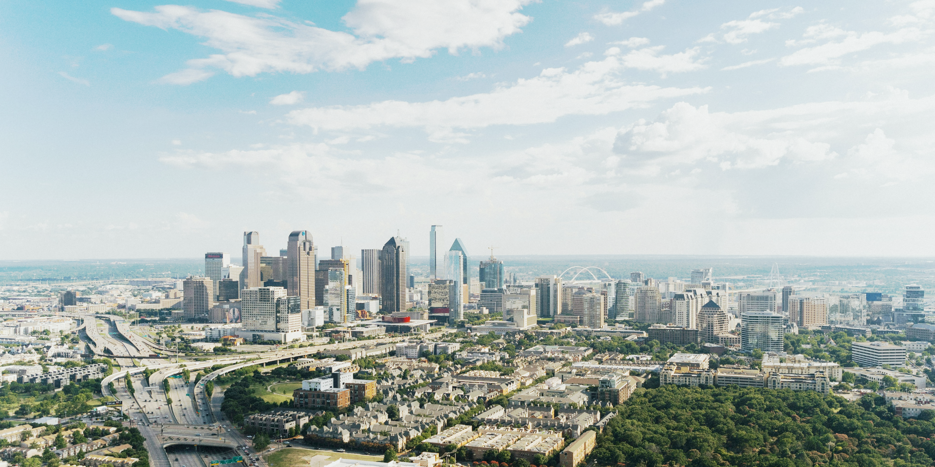 An aerial view of a city skyline with trees in the foreground