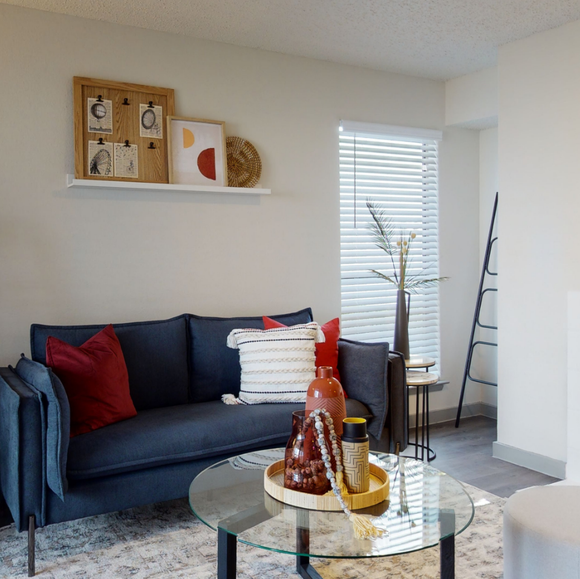 A living room with a blue couch and a glass coffee table