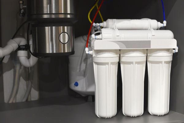 A water filter is sitting under a sink in a kitchen.