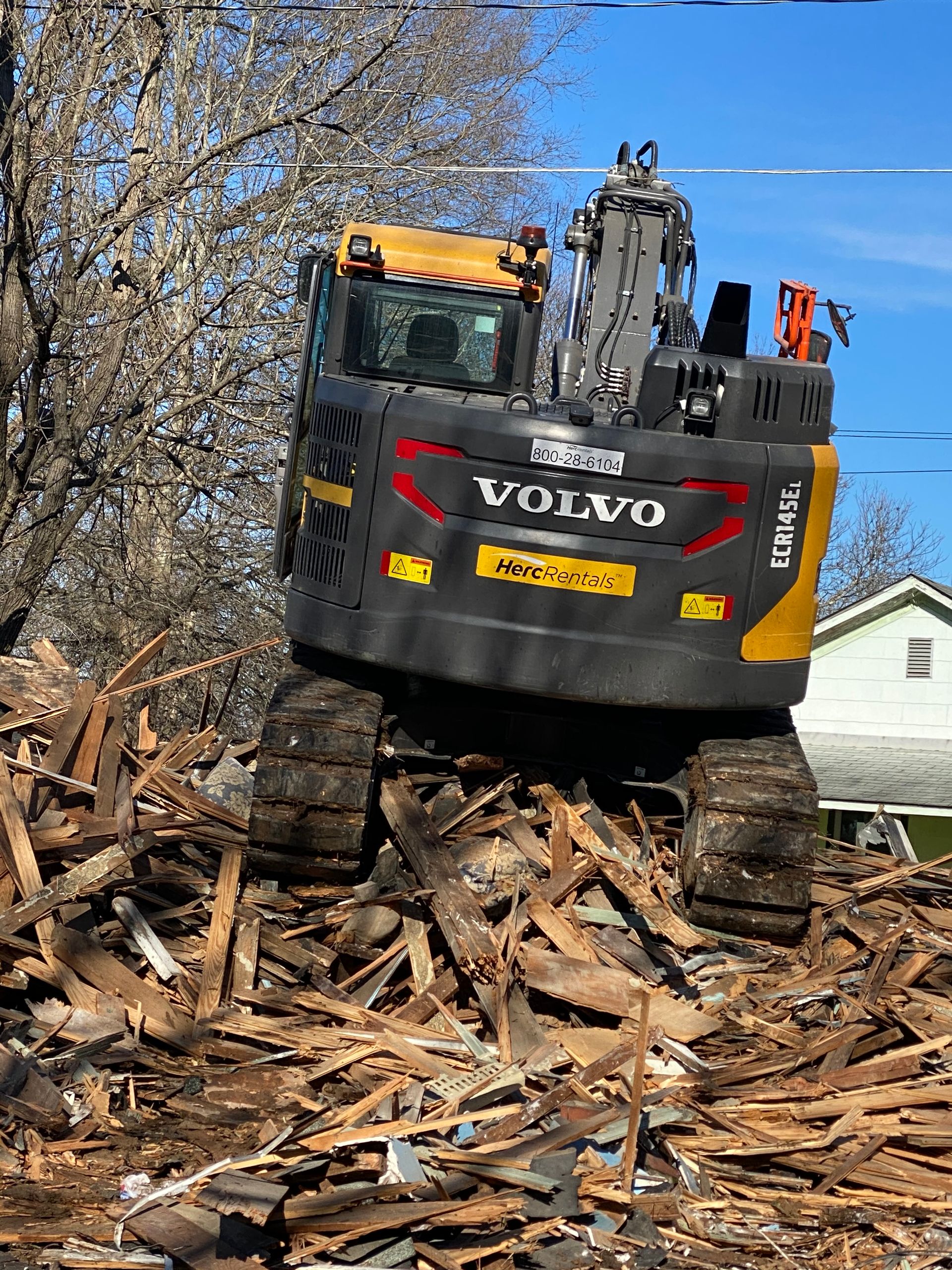 A volvo excavator is sitting on top of a pile of wood.