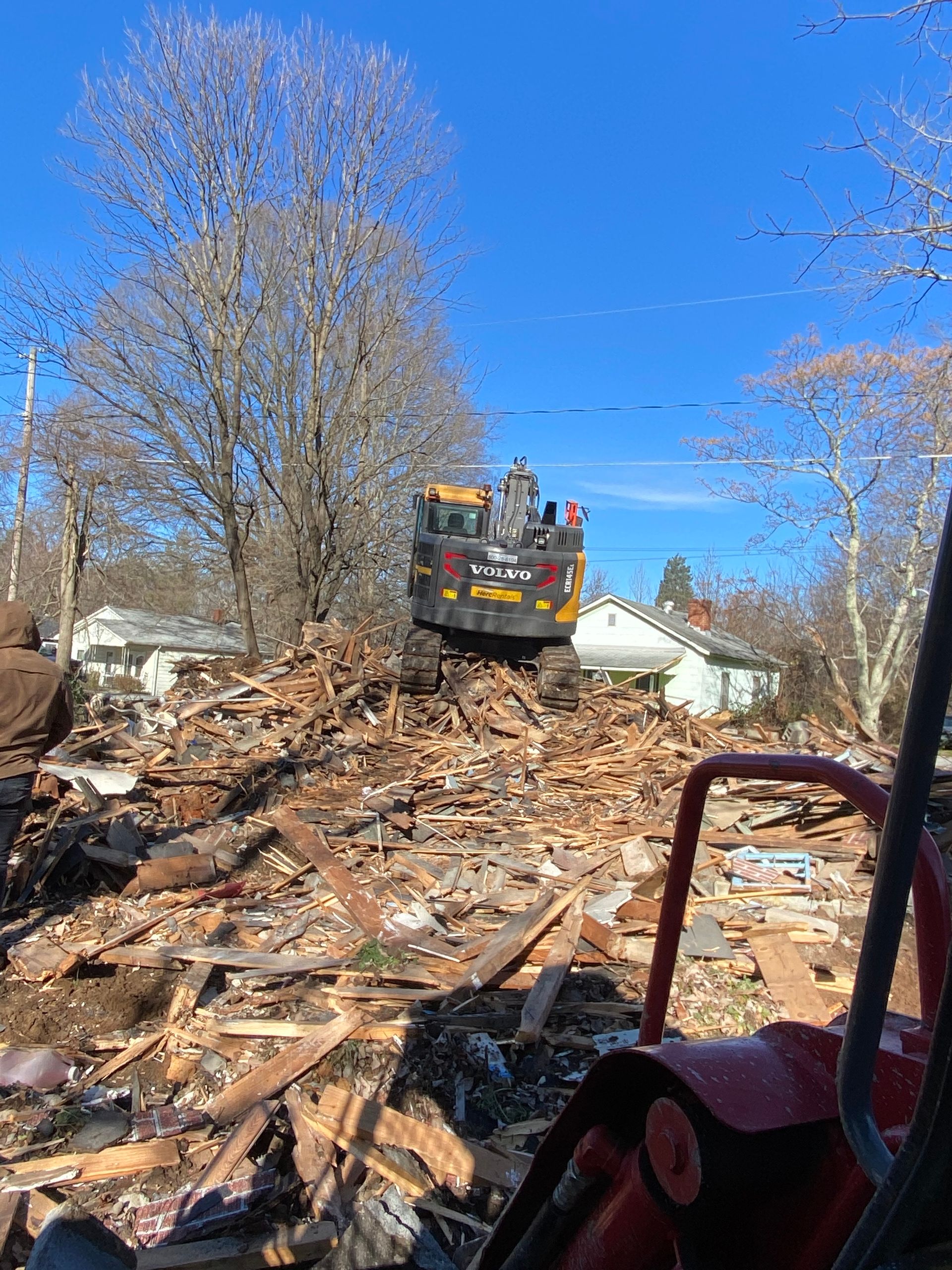 A bulldozer is sitting on top of a pile of wood.