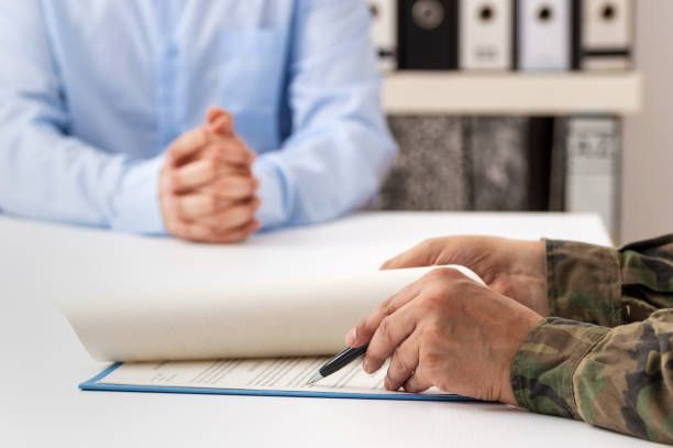 A man in a military uniform is sitting at a table with a man in a blue shirt.