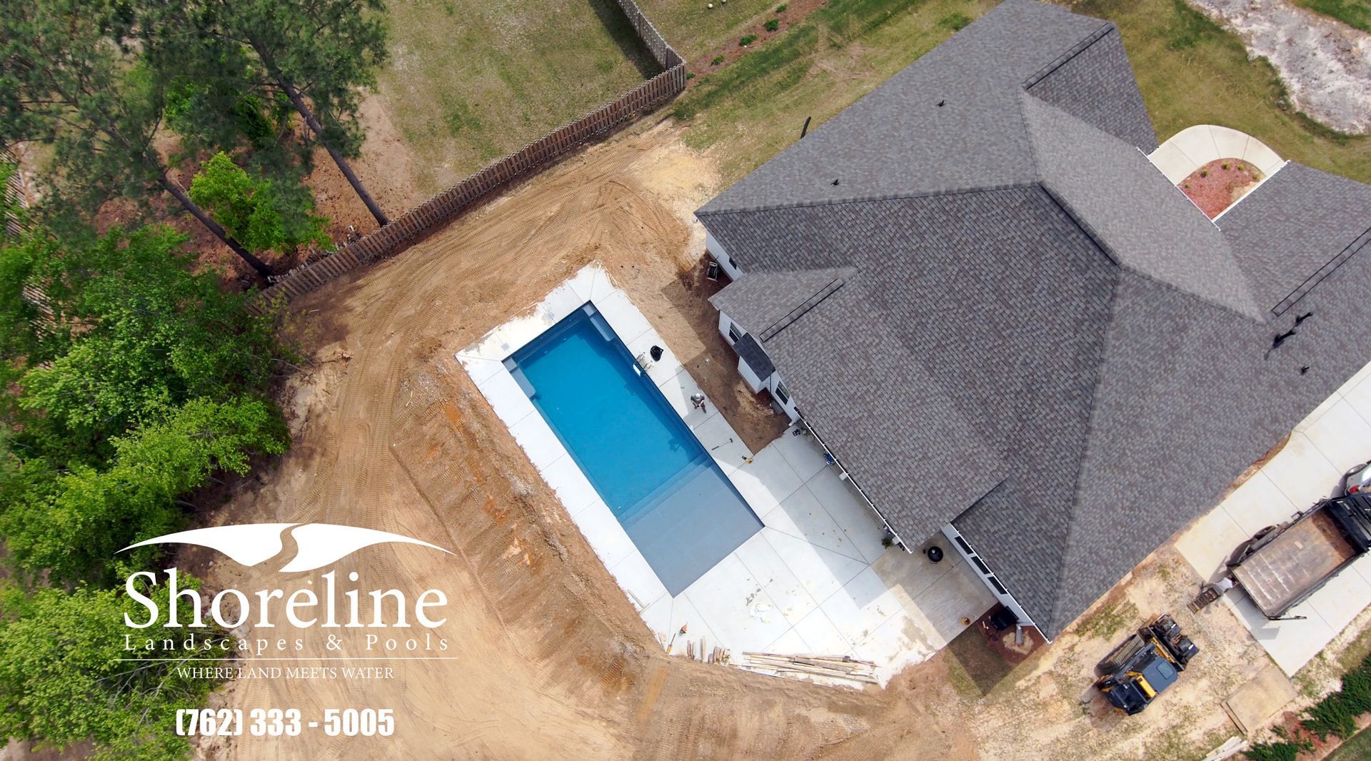 Aerial view of a home with a rectangular pool and light concrete patio. Shoreline Landscaping logo visible.