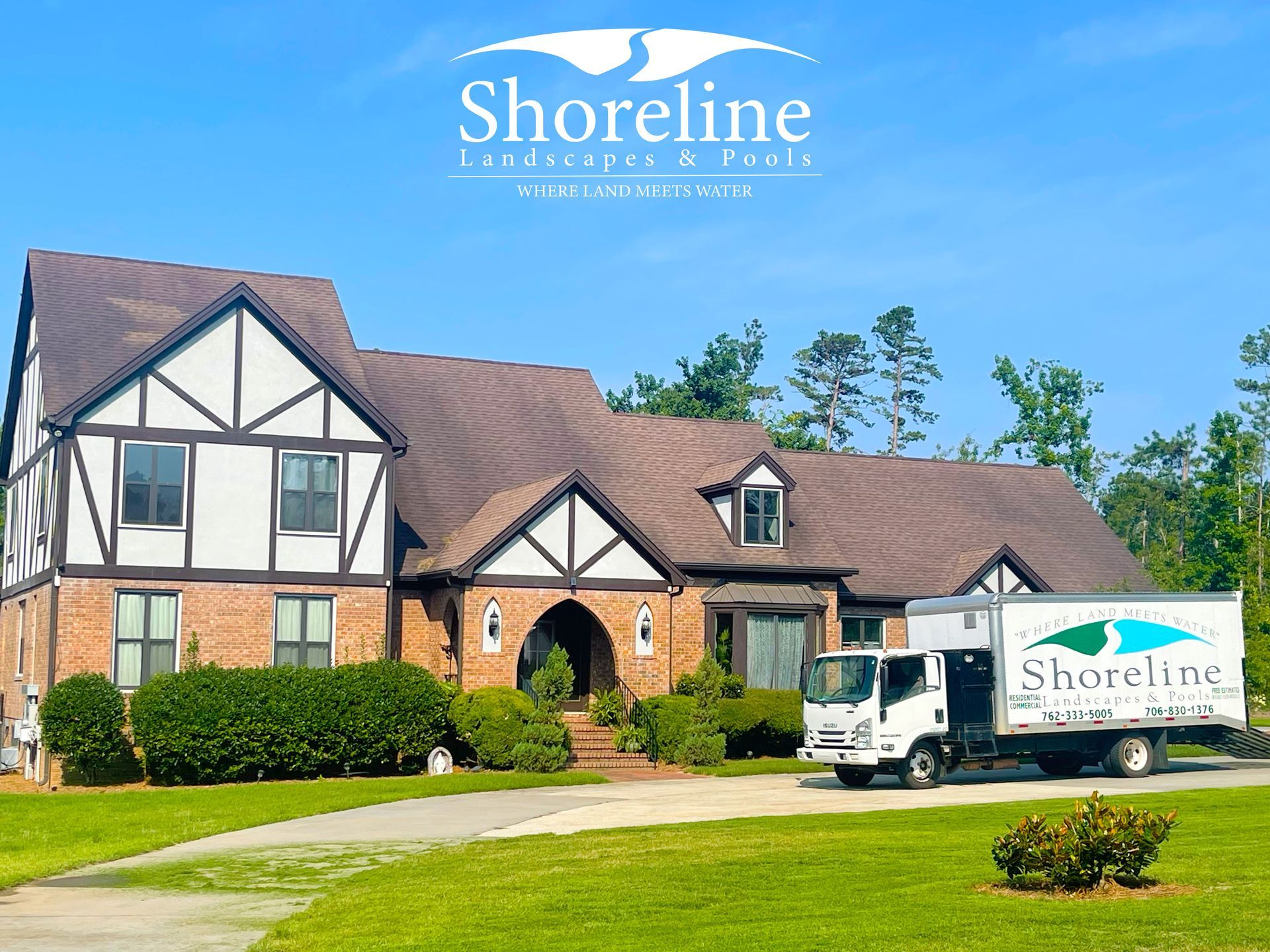 Shoreline Landscapes & Pools truck in front of a Tudor-style home with green lawn.