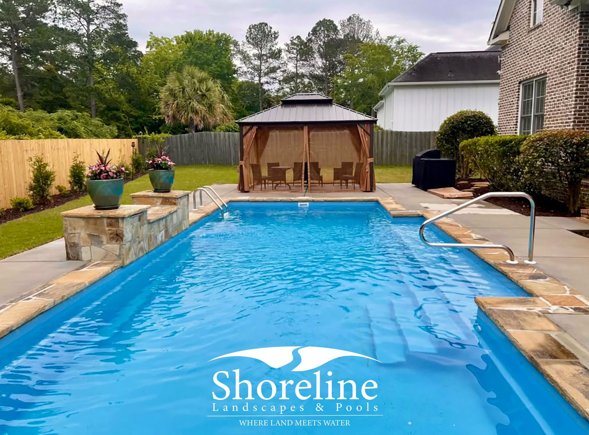 Rectangular pool with gazebo and landscaping in backyard.