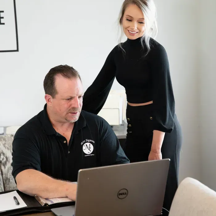A woman is standing next to a man using a dell laptop