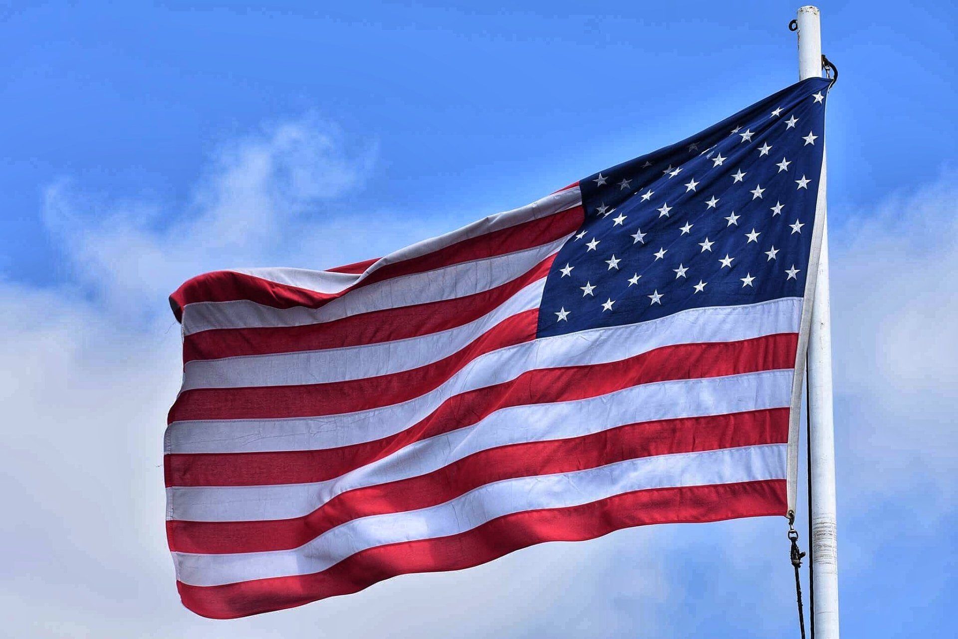 An american flag is waving in the wind against a blue sky