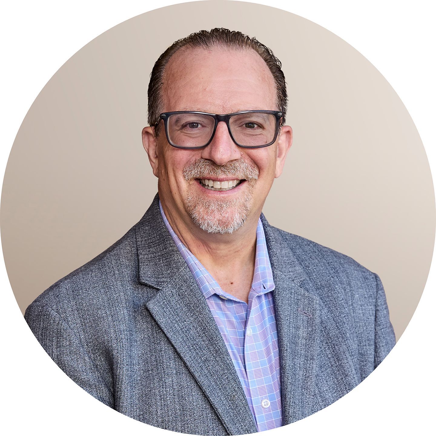 A man with glasses and a beard is wearing a suit and tie.