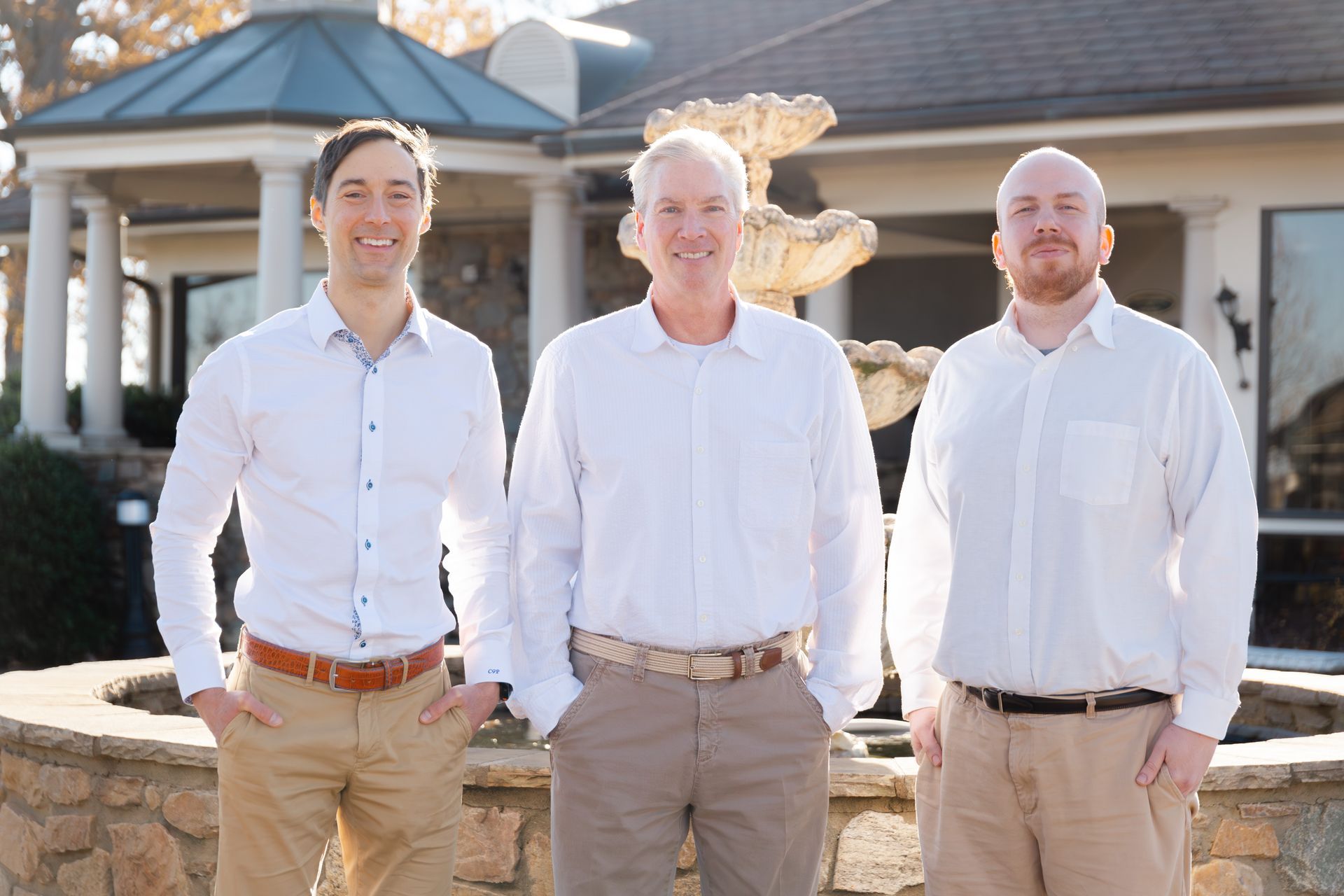 Three men are posing for a picture in front of a fountain.