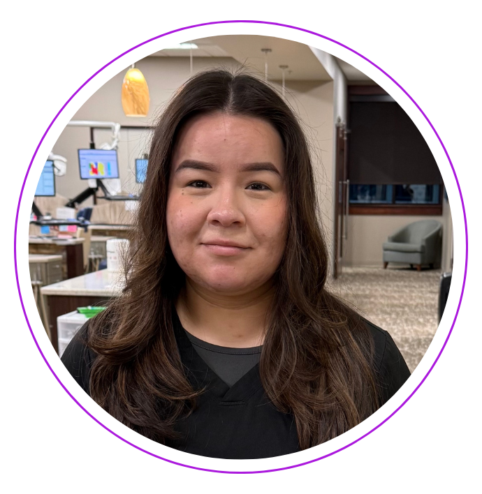 Monica R., in a black top, smiles inside the Small and Piers dental office. 