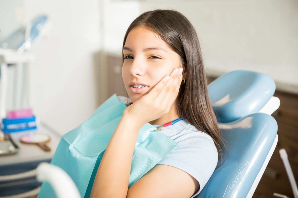 Person sitting in a dental chair with a bib, smiling in a dentist’s office