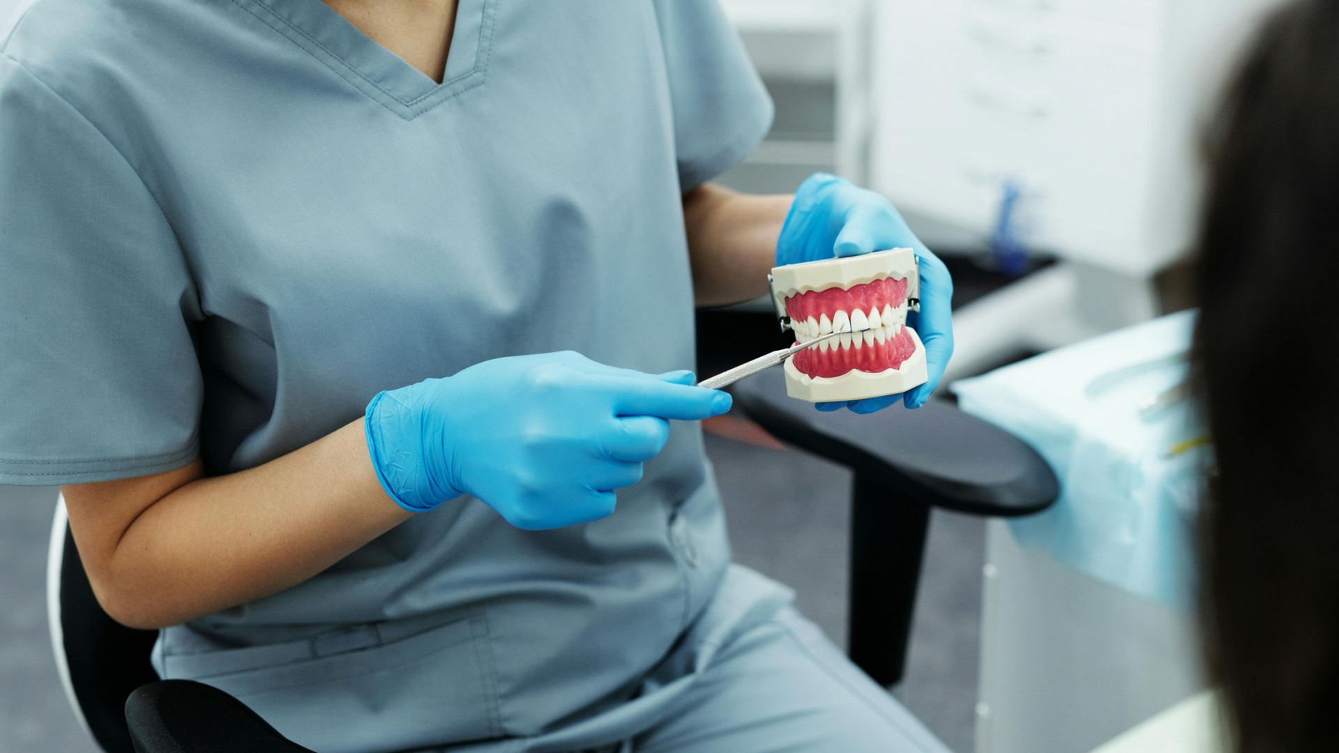 Dentist holding a model of teeth, showing a patient and explaining details of their treatment