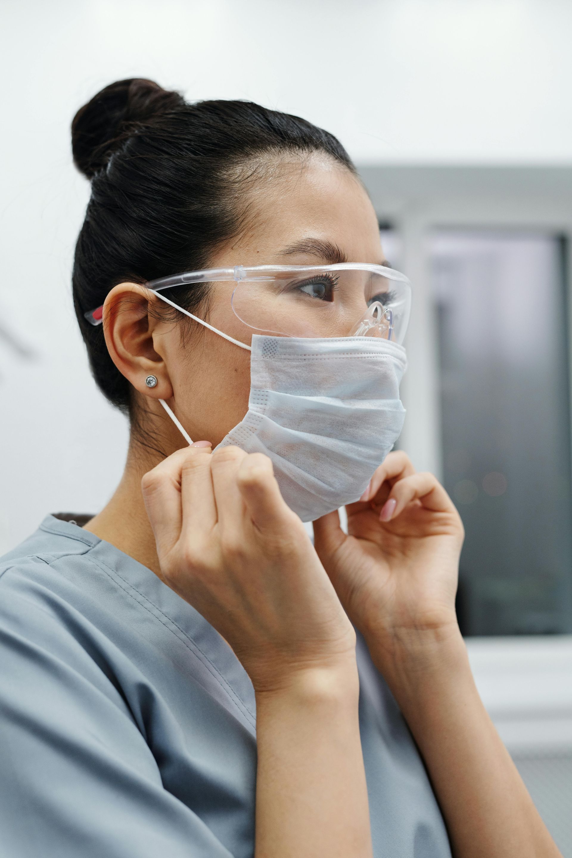 A nurse is putting on a mask and goggles.