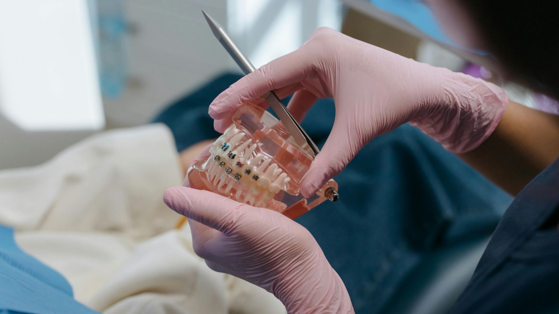 Dentist holding a model of teeth with braces, showing a patient how to keep the braces protected
