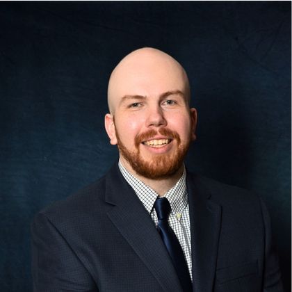 A bald man with a beard wearing a suit and tie