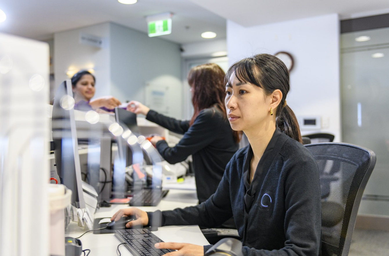 People gathered in an eyeglass shop, socializing around a table with food and drinks.