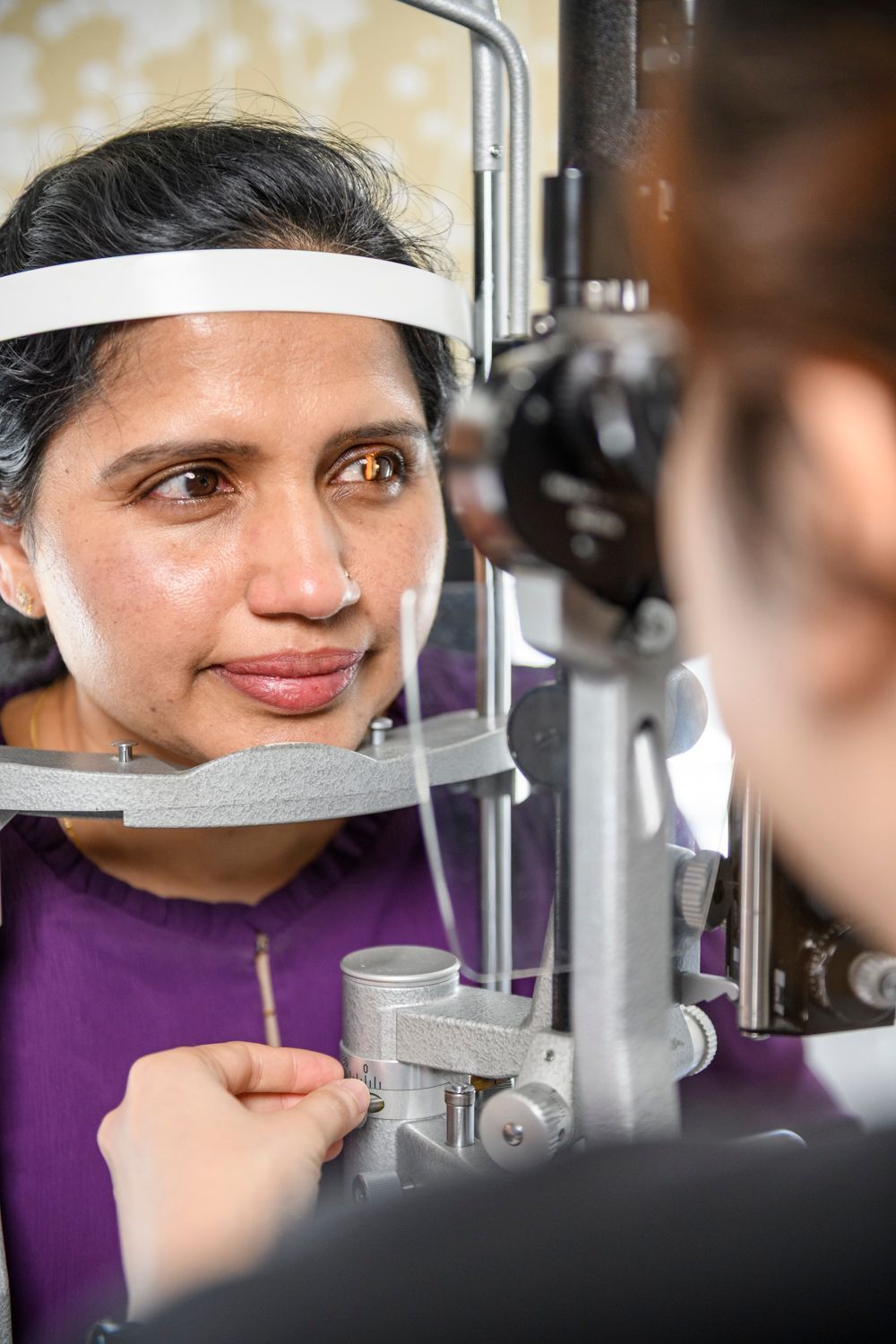 Woman undergoing an eye exam with an eye doctor using a slit lamp; focused on eye.