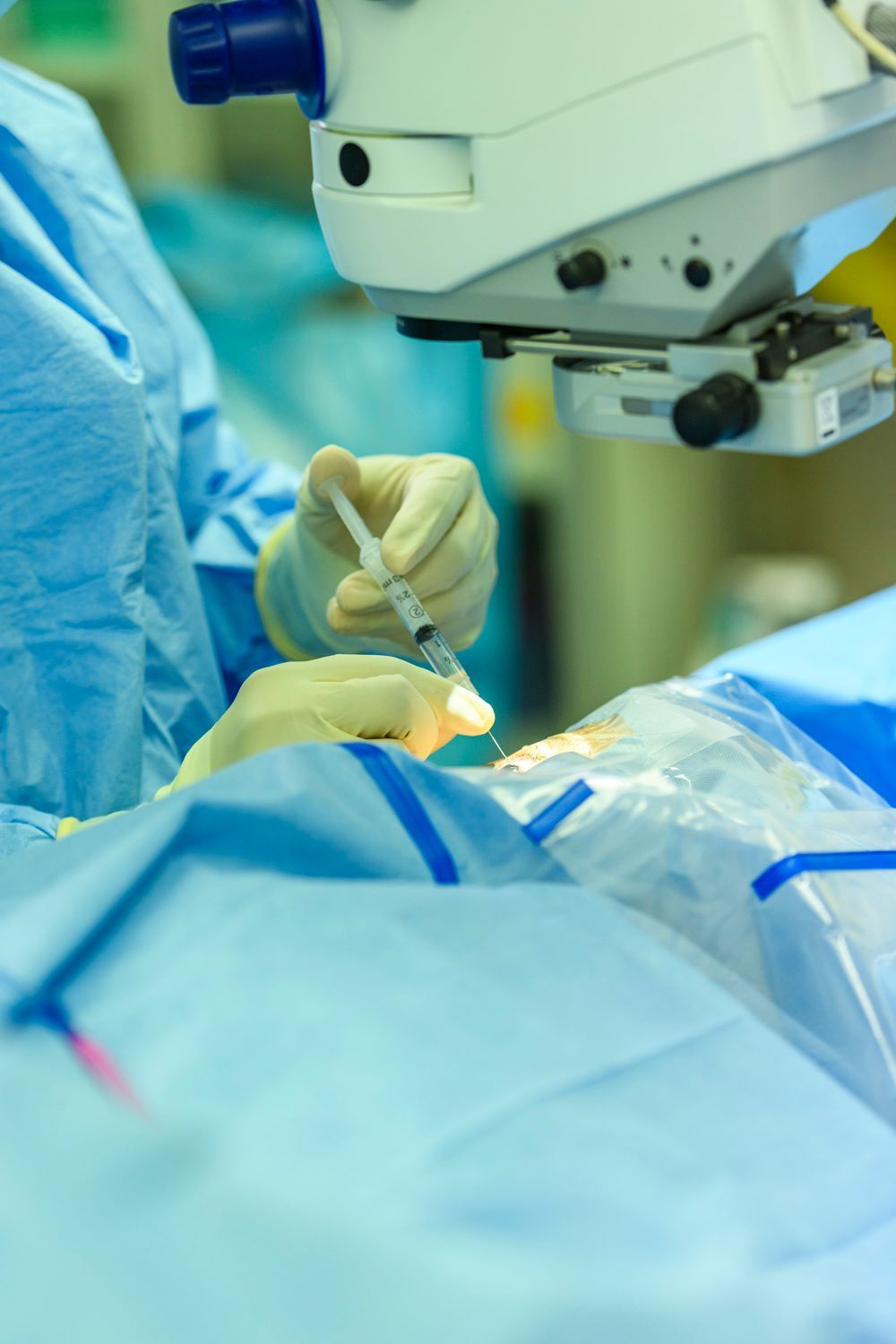 Doctor in surgical mask holding syringe, operating room setting.