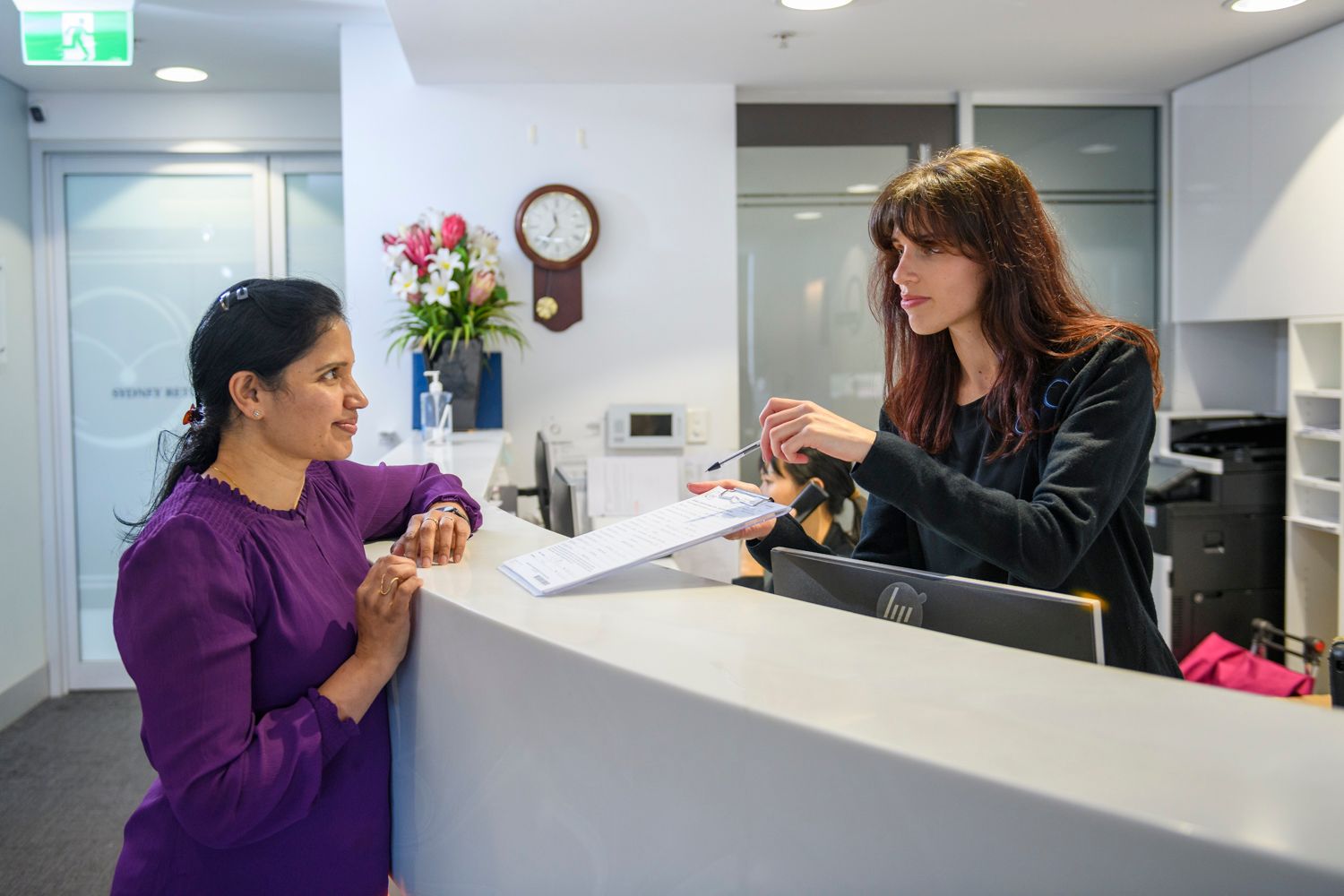 Three people wearing blue surgical scrubs and caps smile.