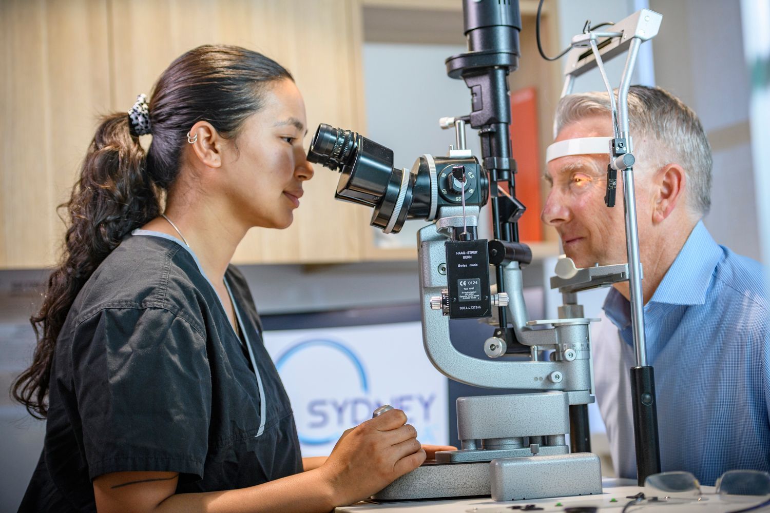 Optometrist examining a patient's eyes with a slit lamp in a clinic.