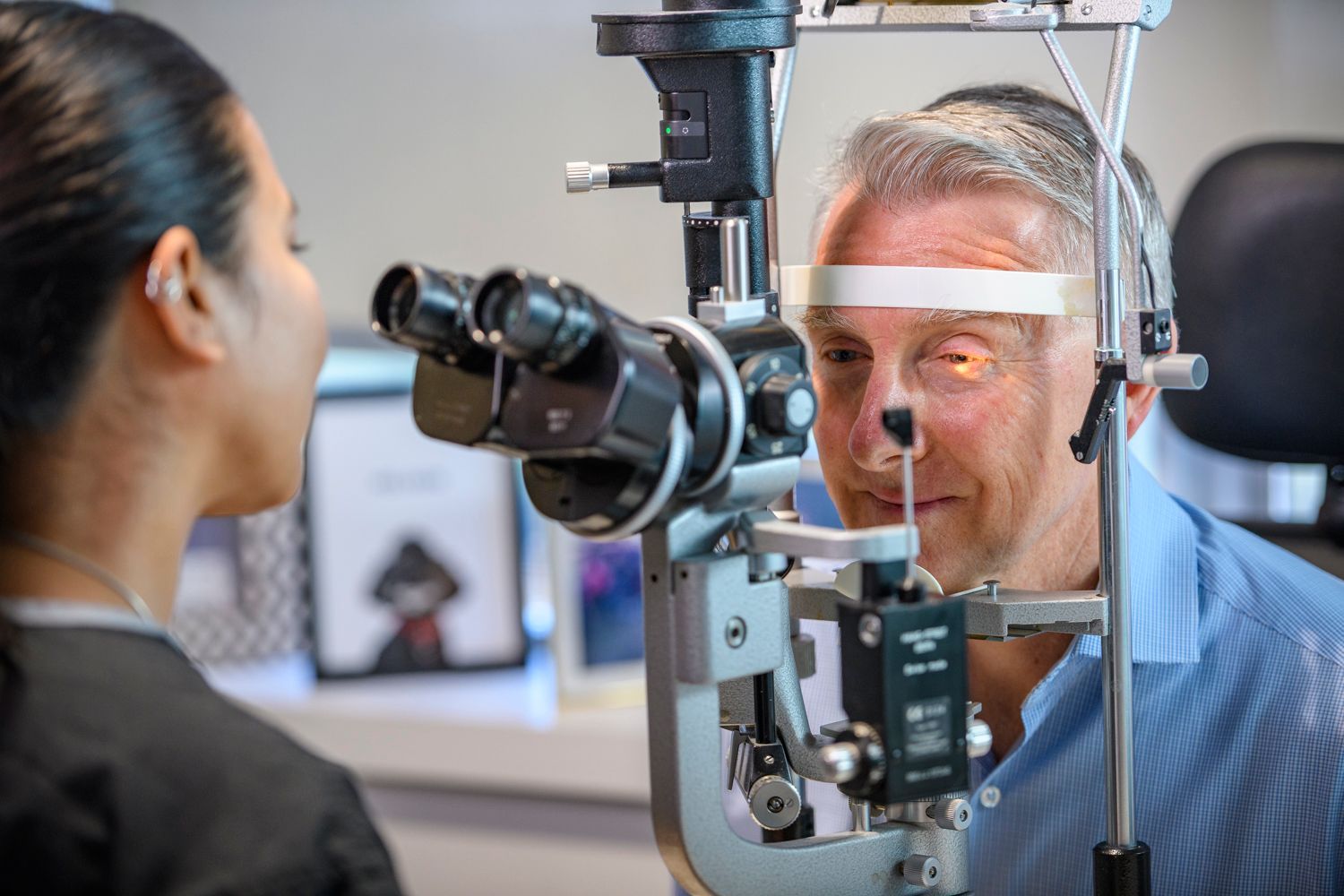 A person receiving an eye exam from a healthcare provider using a slit lamp in a medical office.