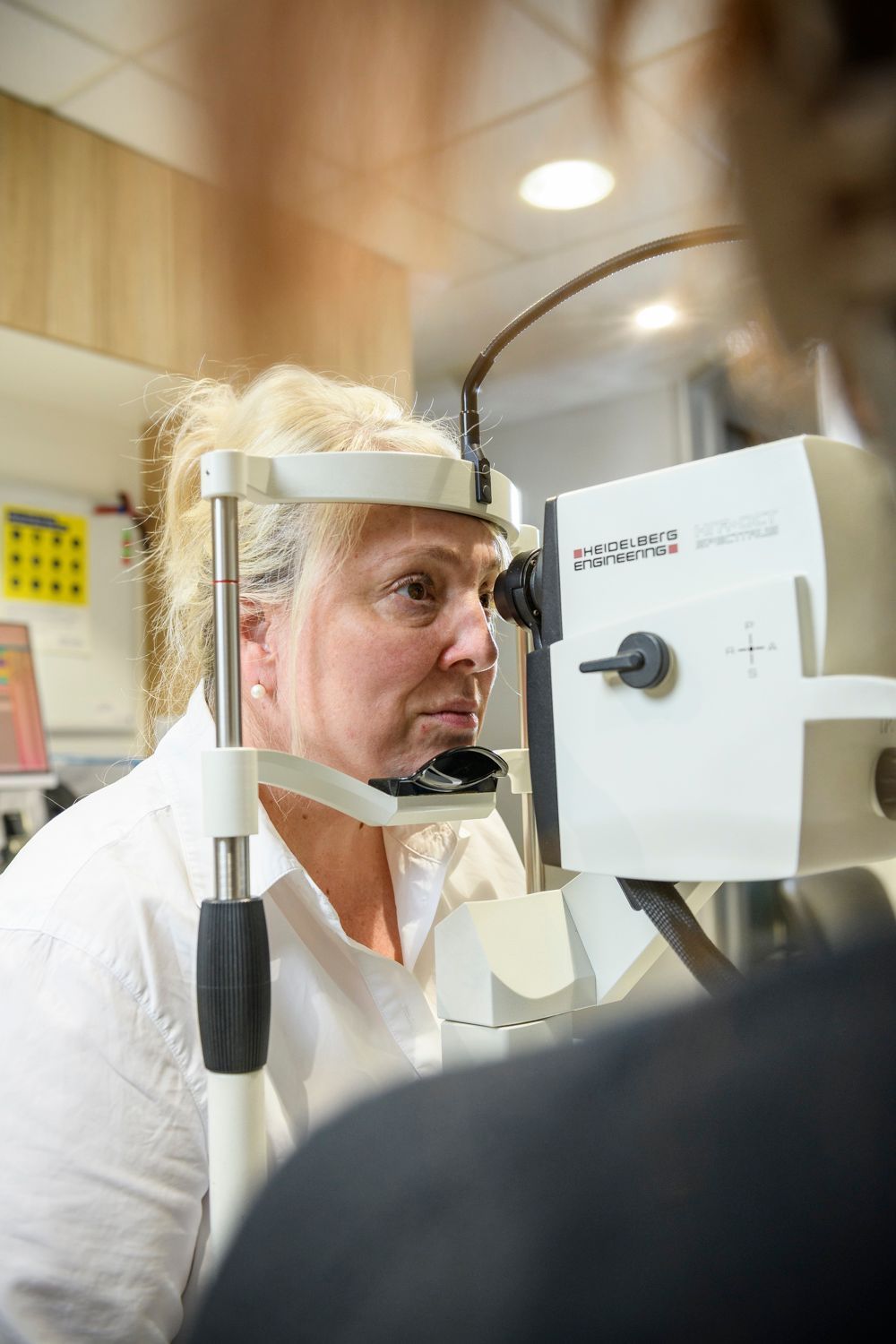 Woman undergoing eye exam with an ophthalmoscope.
