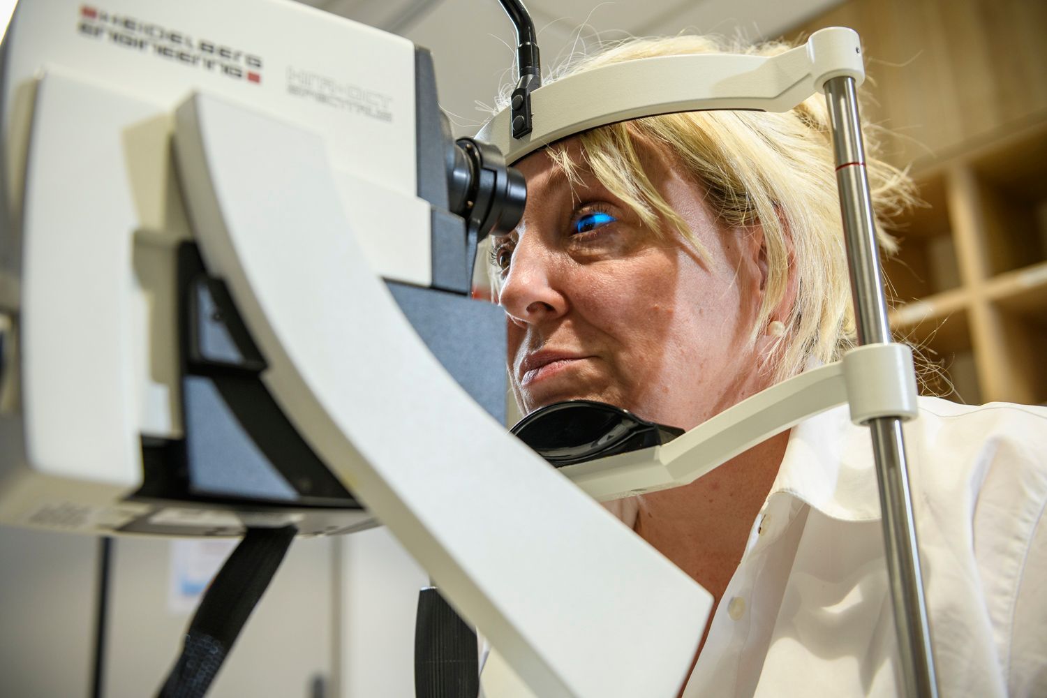 Woman undergoing eye exam with specialized equipment in a clinic setting.