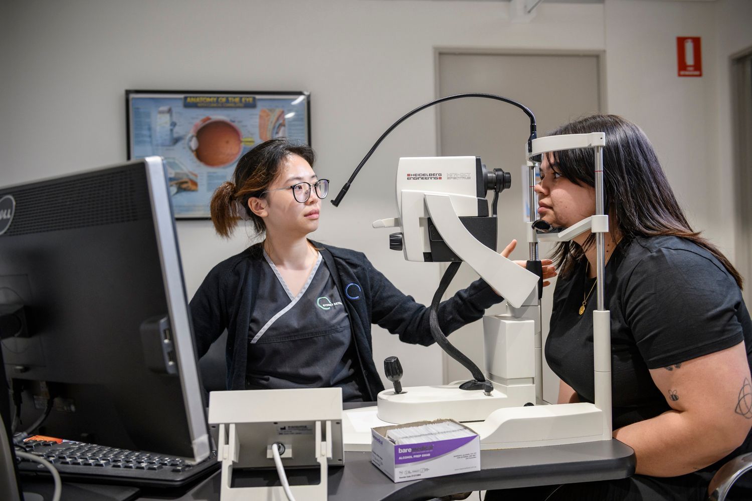 Optometrist examining a patient's eyes with a slit lamp in an eye clinic.
