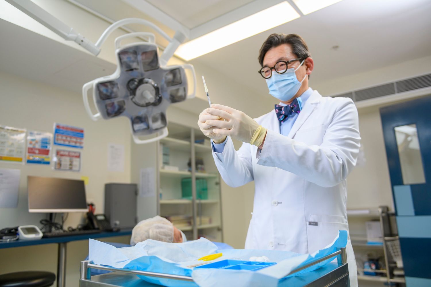 Woman undergoing an eye exam, peering into a slit lamp. White lab coat, neutral-toned room.