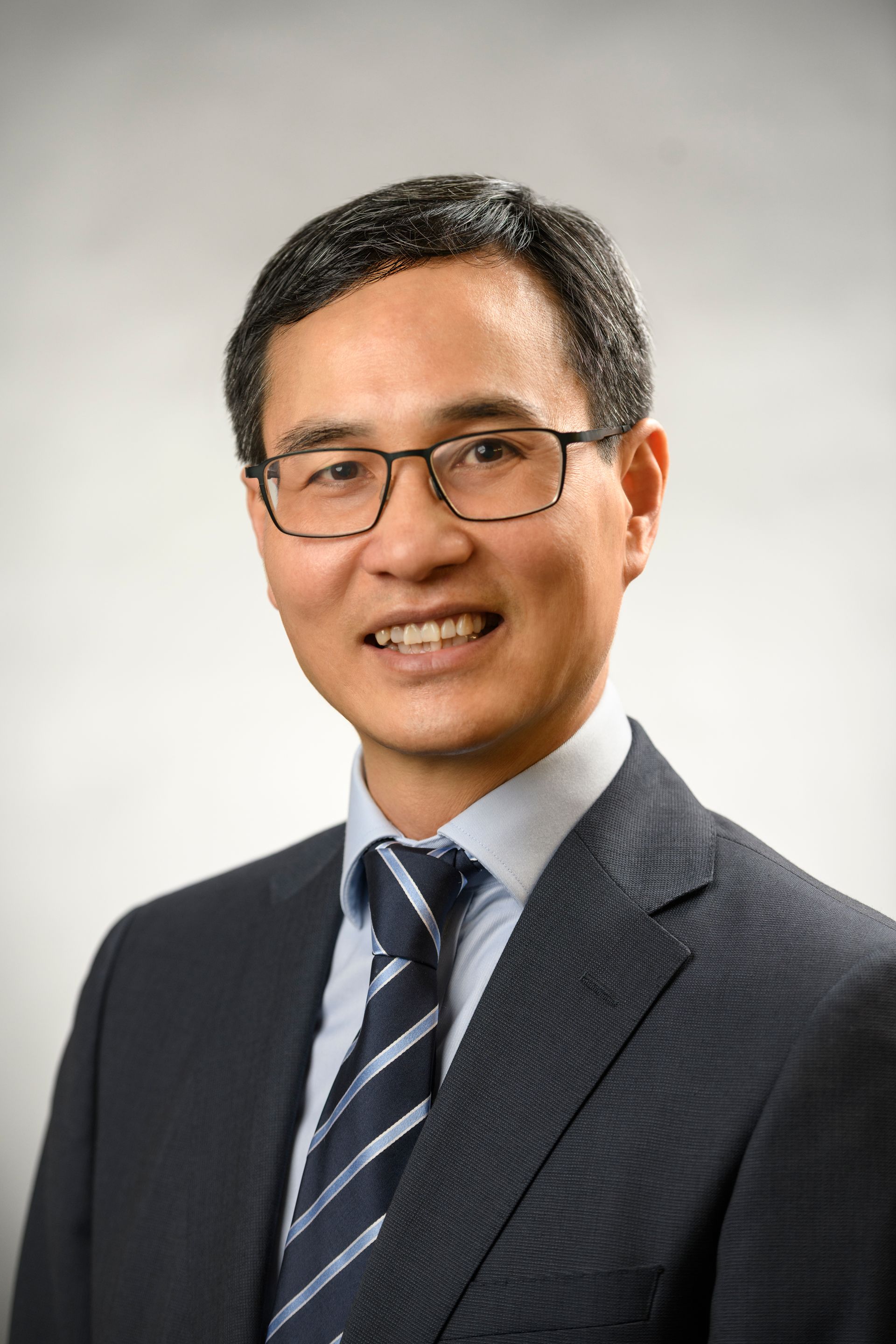 Man in glasses and suit, looking forward with a slight smile.