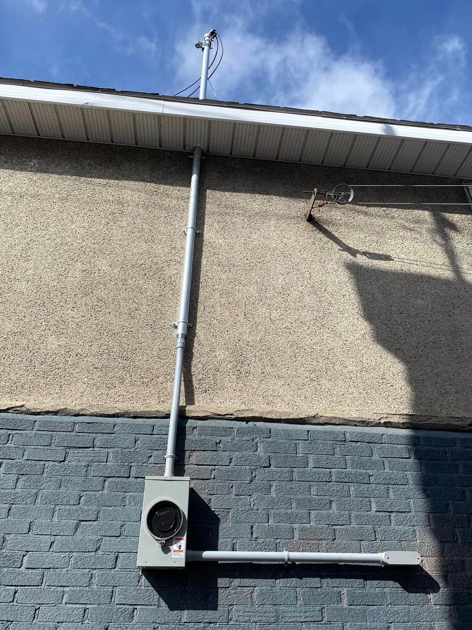 Un mur de briques auquel est fixé un wattmètre.