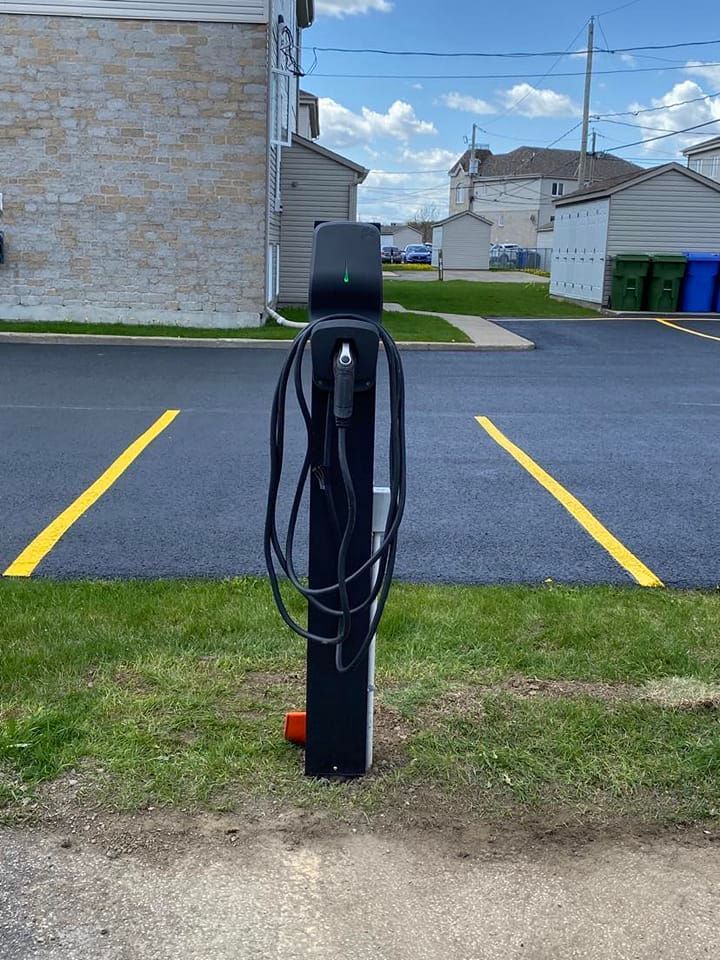 Il y a une borne de recharge au milieu d'un parking.