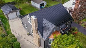 An aerial view of a house with a black roof and a garage.