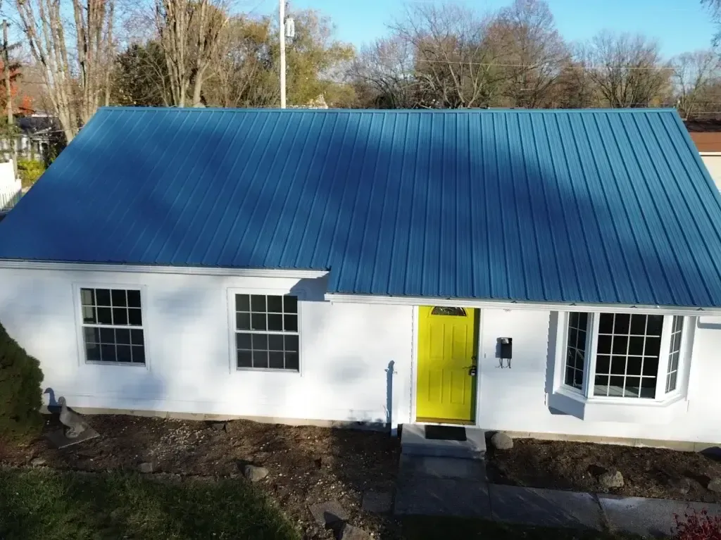 A white house with a blue roof and a yellow door