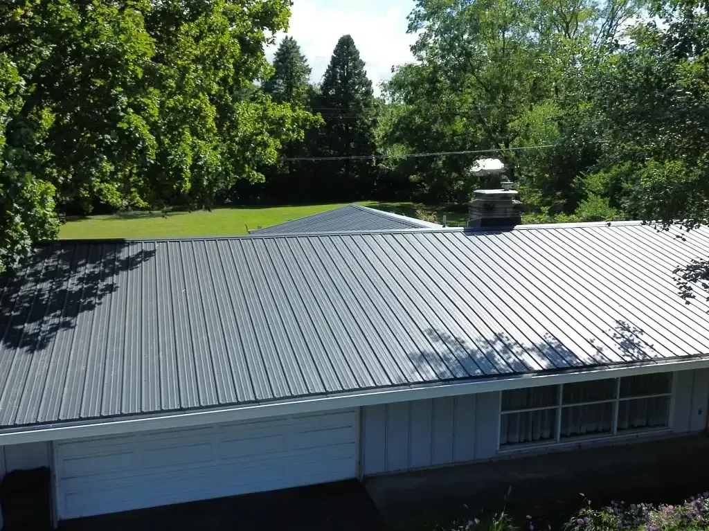 An aerial view of a house with a metal roof and trees in the background.