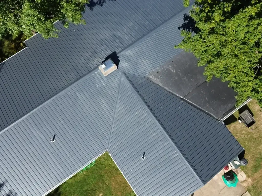 An aerial view of a house with a gray roof surrounded by trees.