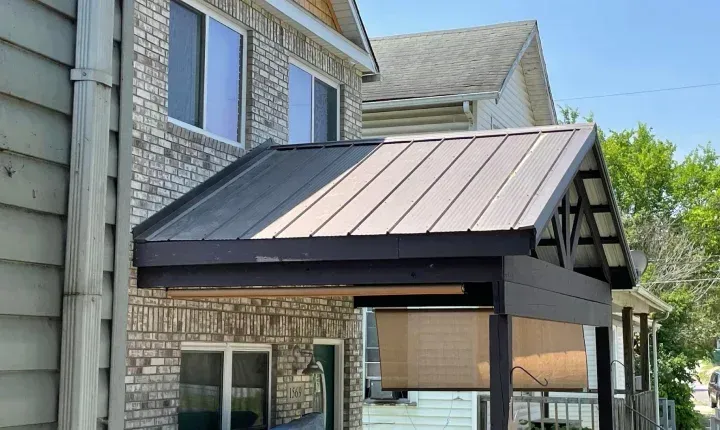 A brick house with a metal roof and a porch.