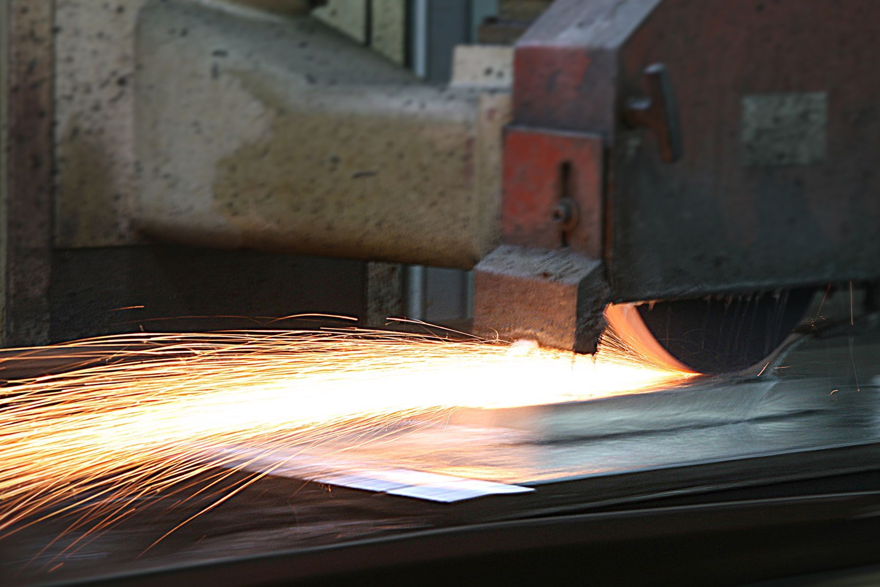 Une machine broie un morceau de métal d'où sortent des étincelles.