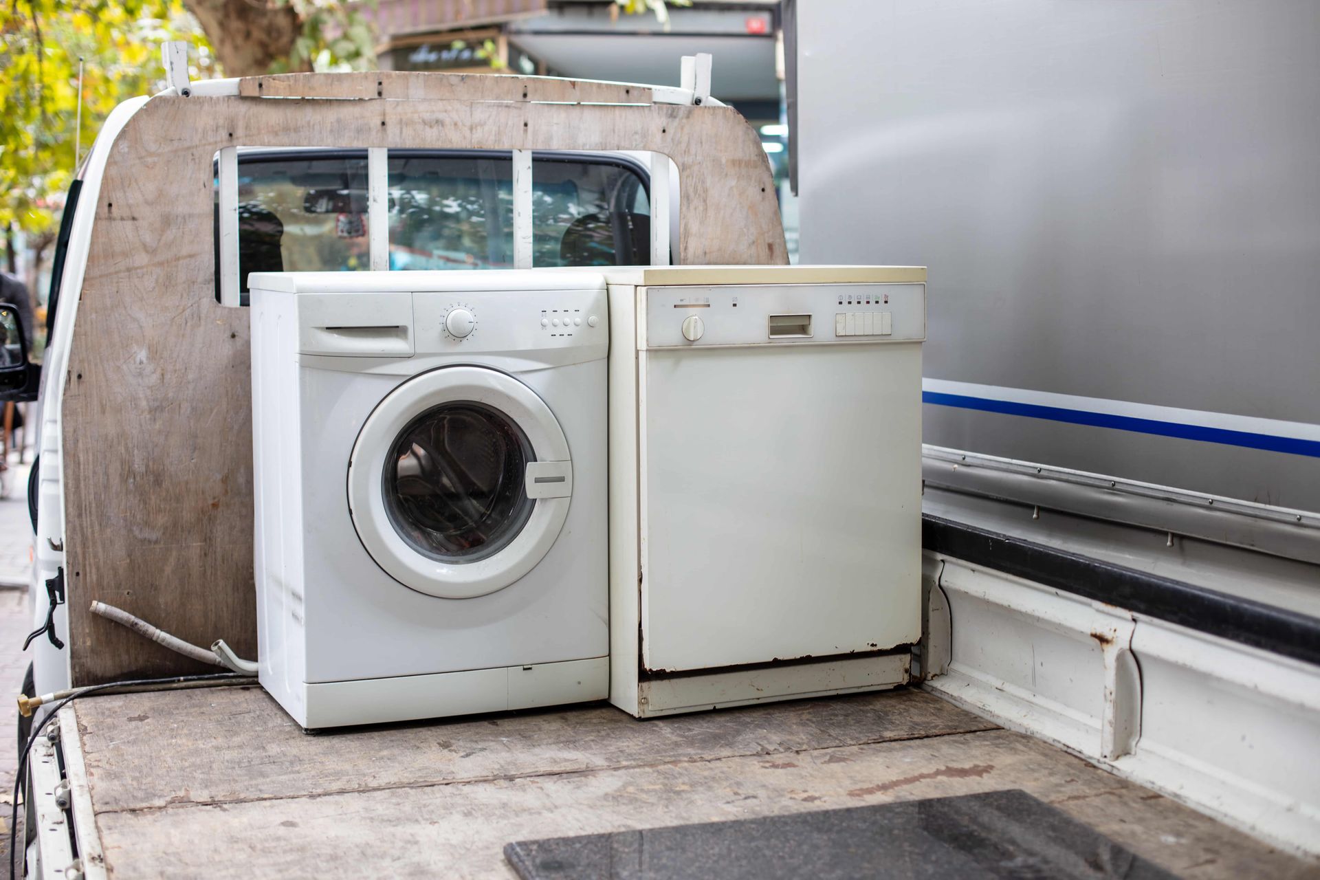 Washing machine and dishwasher on the back of a truck, ready for removal.