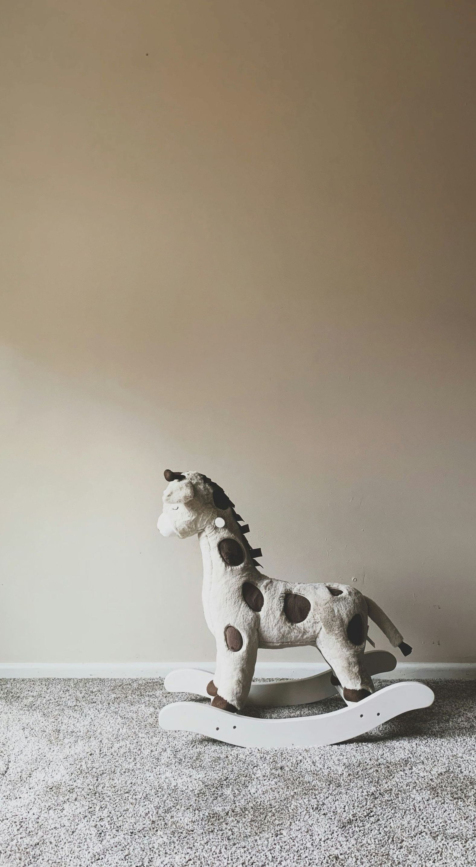 A rocking horse is sitting on a carpet in a room.
