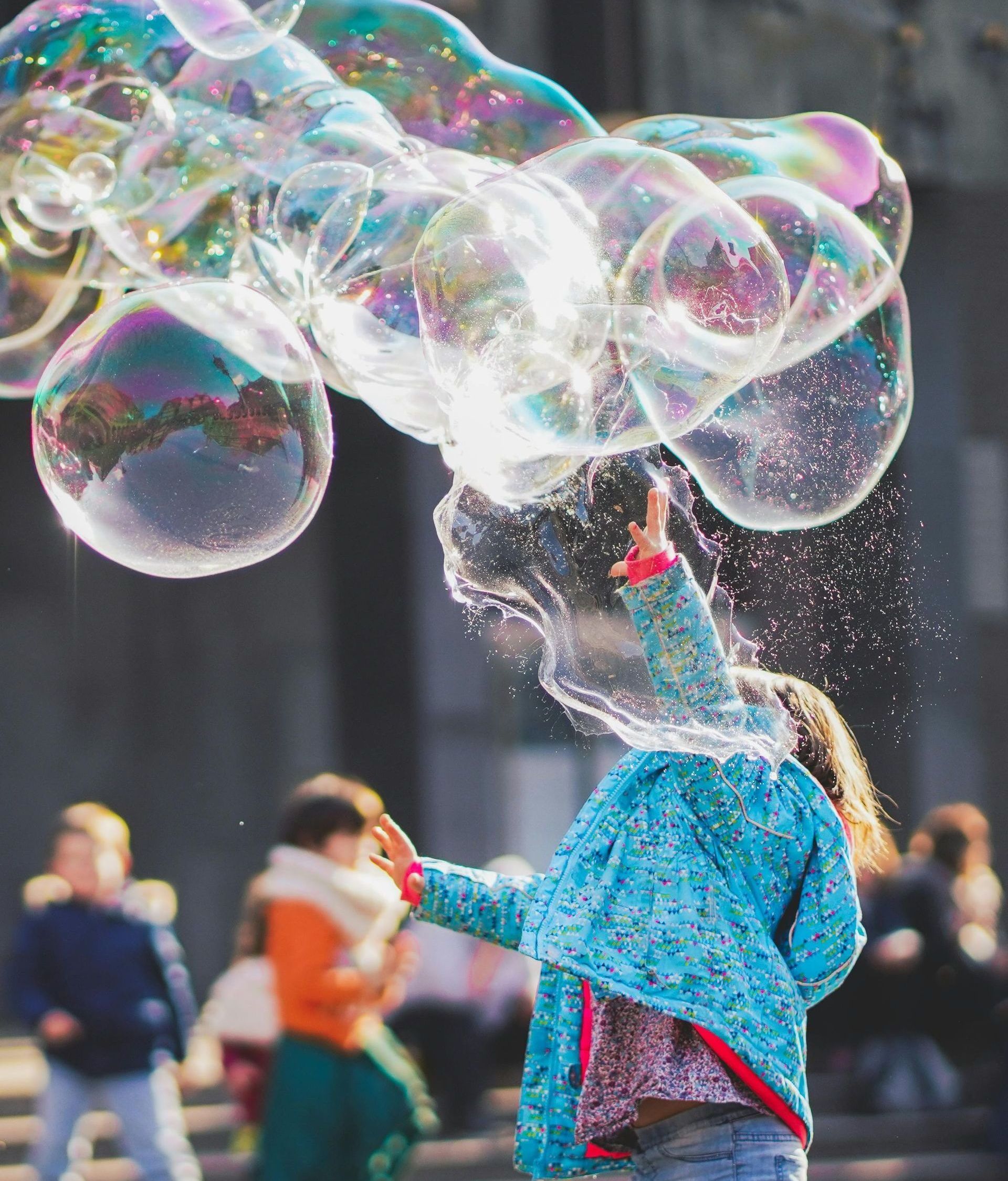A little girl is blowing soap bubbles in the air.