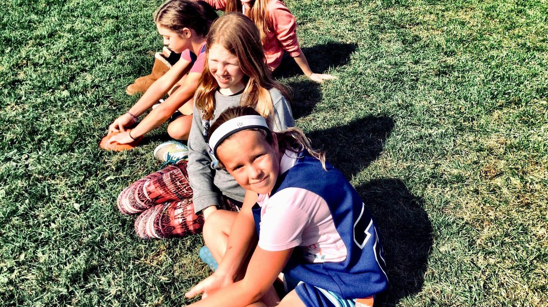 A group of young girls are sitting on the grass.