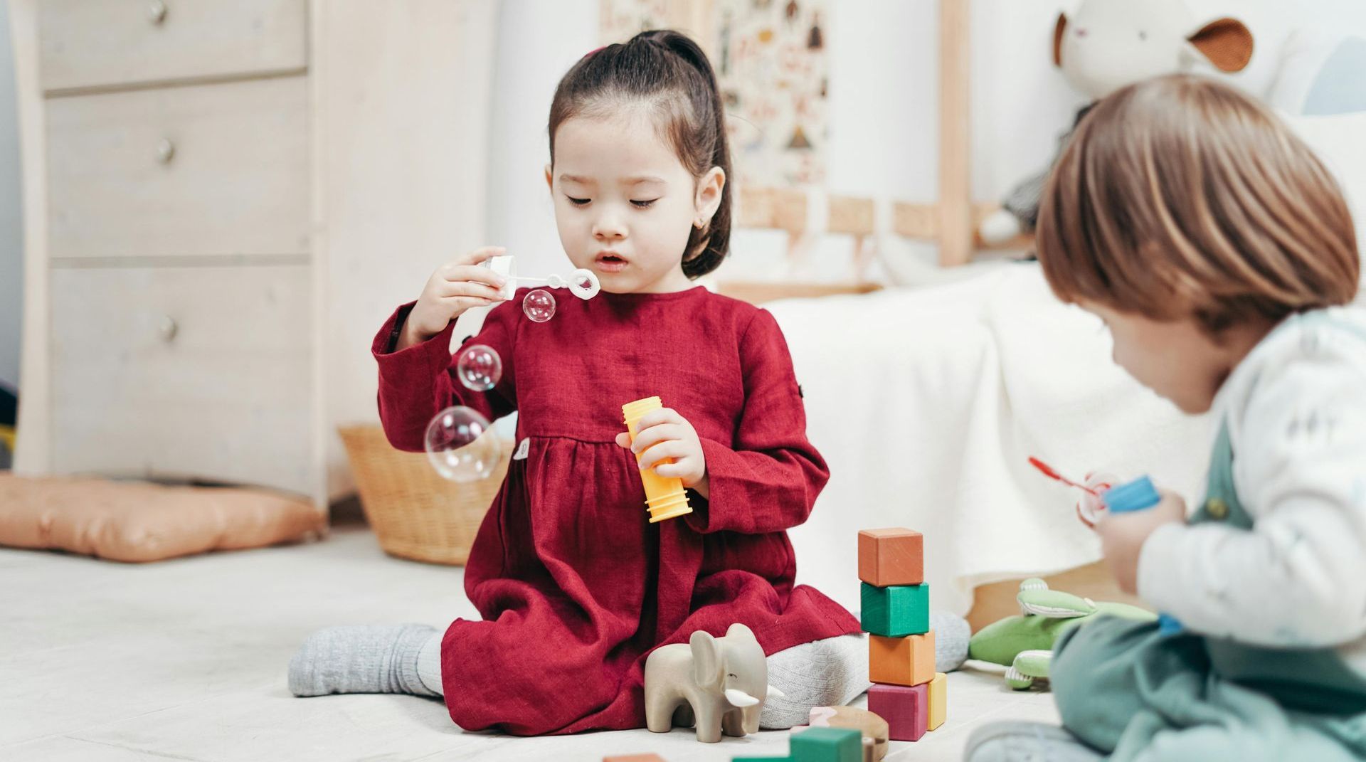 A toy bike is sitting on the floor in a room filled with toys.