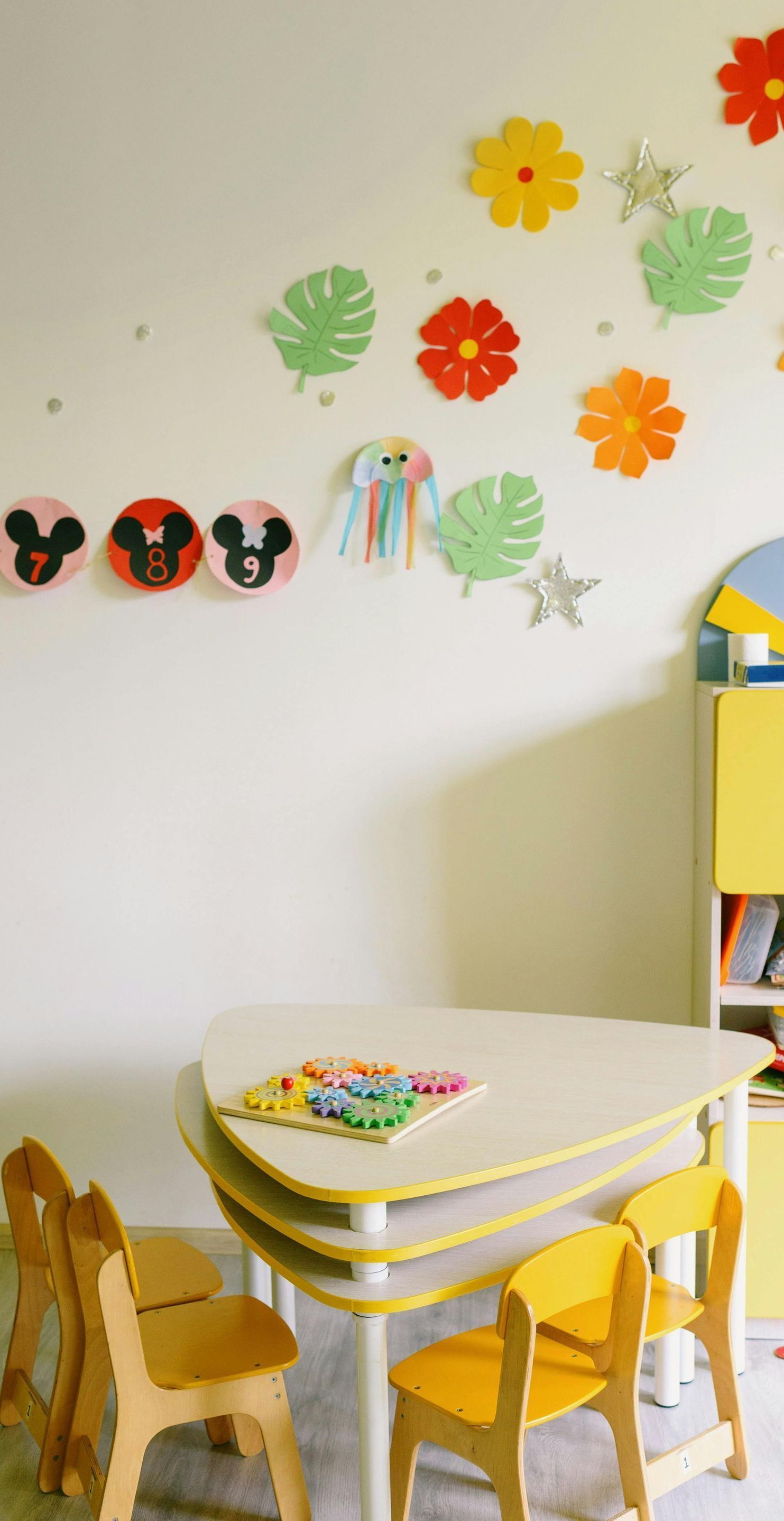A room with a table and chairs and flowers on the wall.