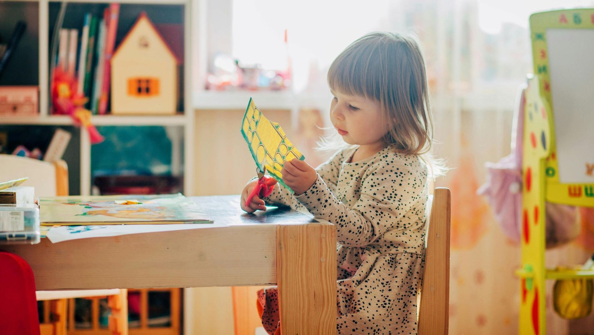 A little girl is playing with wooden animals on a table.
