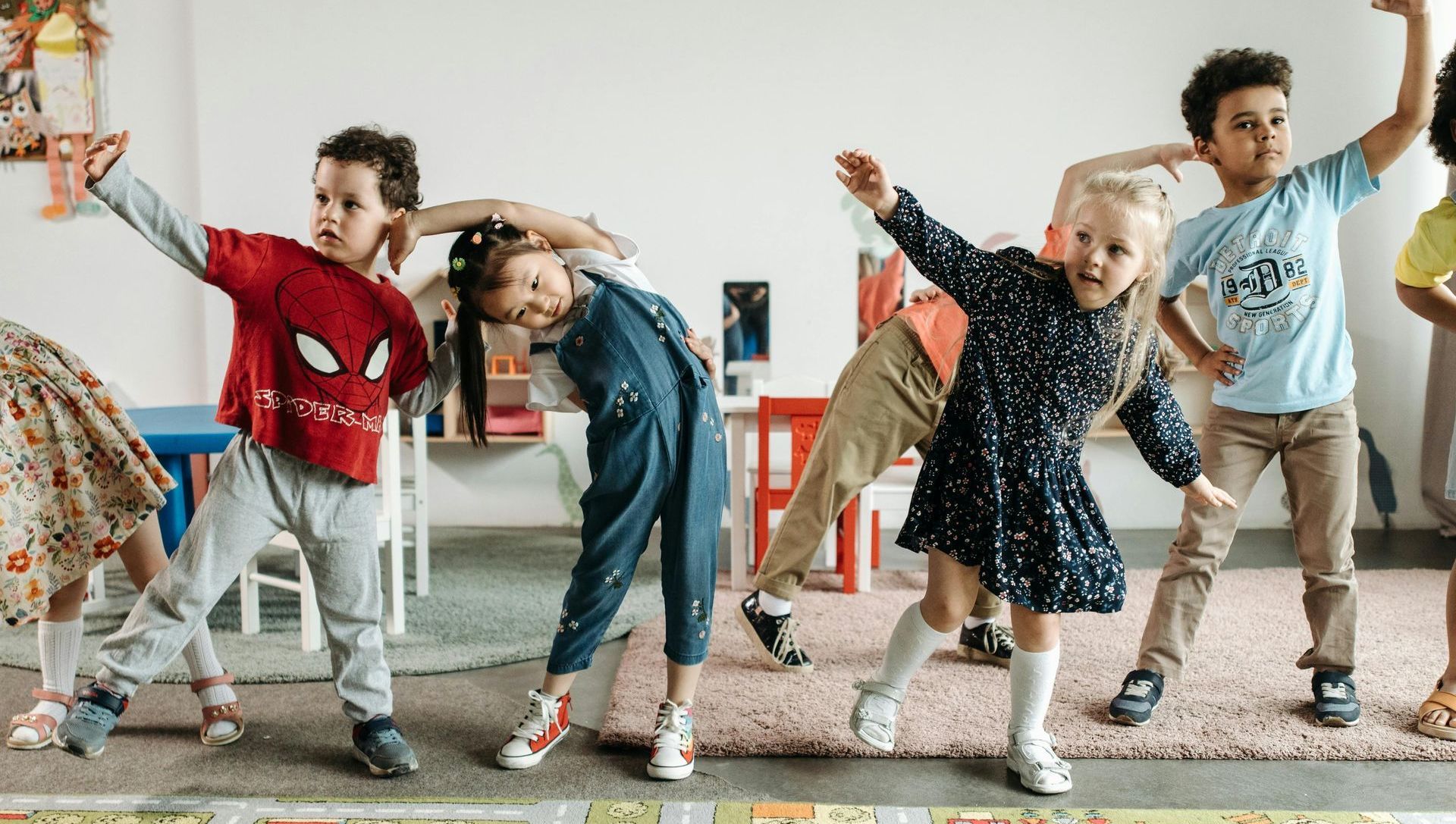 A group of children are dancing together in a classroom.