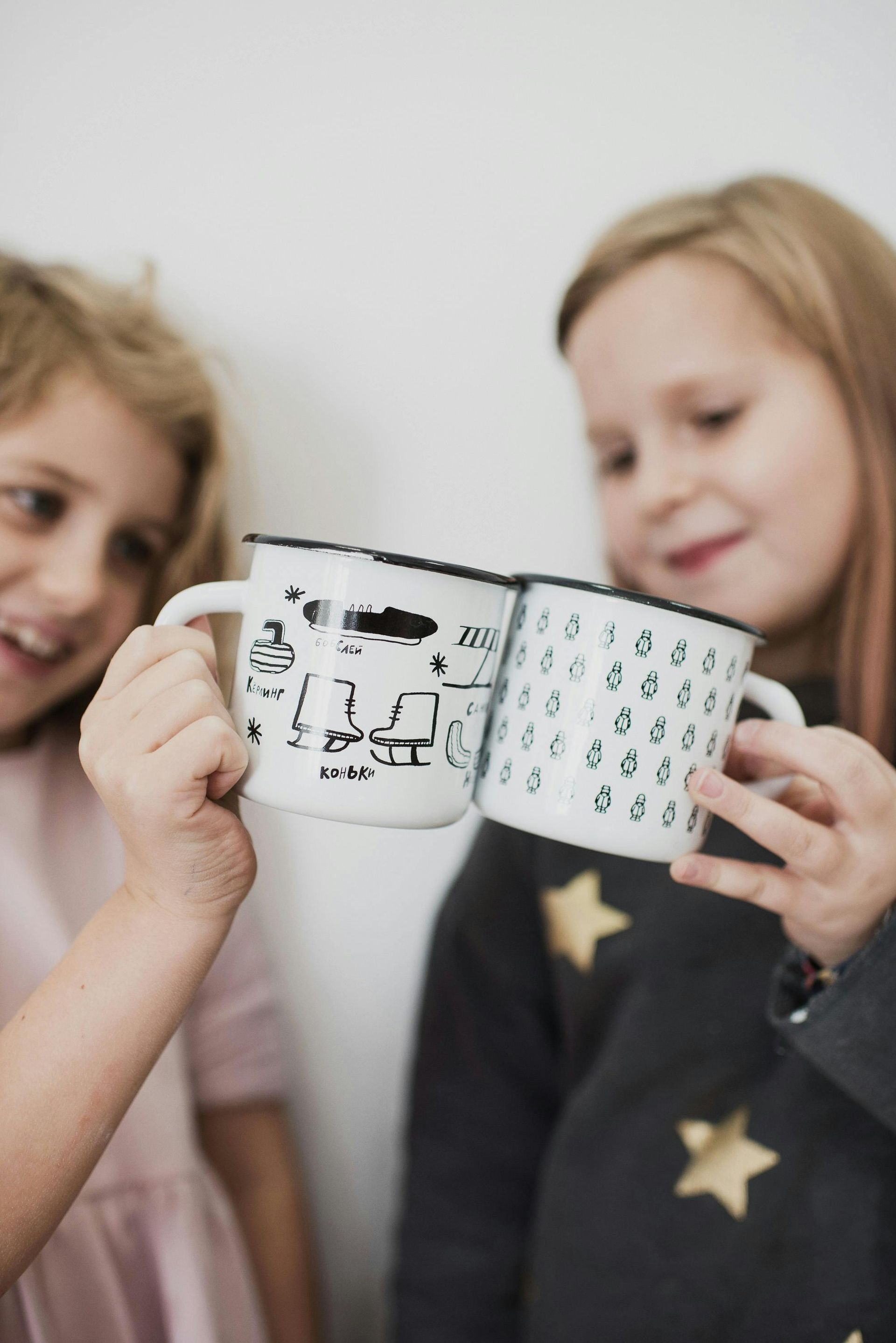 Two little girls are holding mugs in their hands.