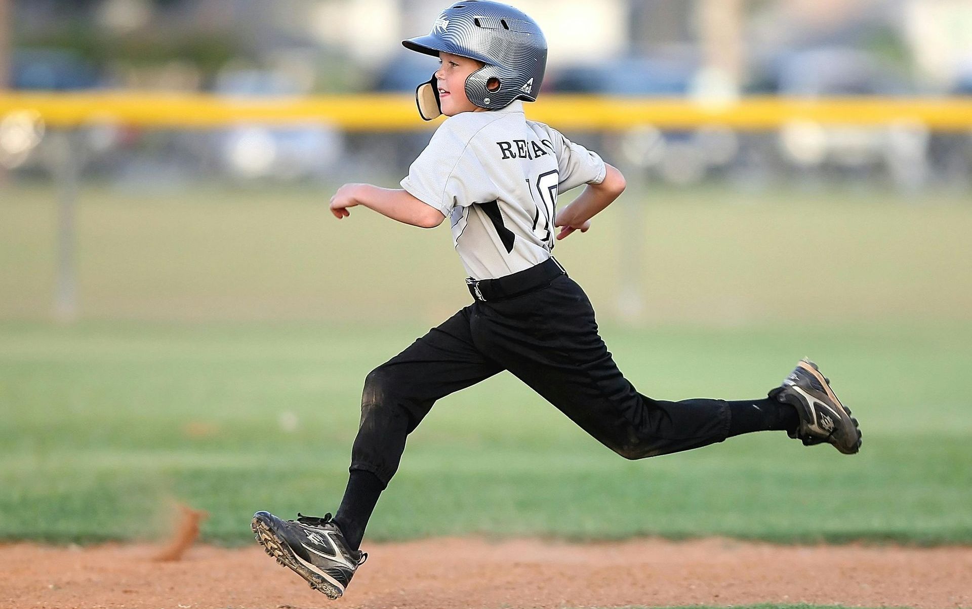 A young boy is running on a baseball field.