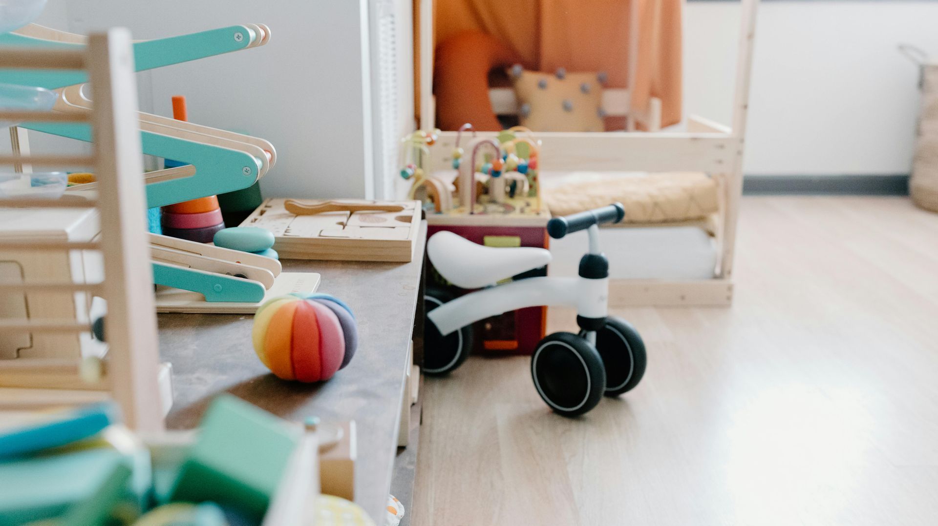 A toy bike is sitting on the floor in a room filled with toys.